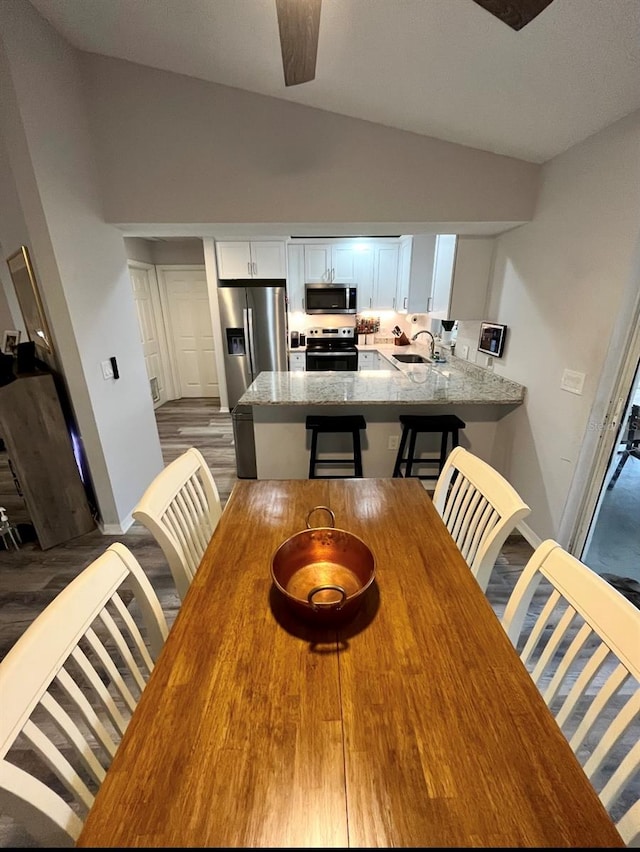 dining area with vaulted ceiling, ceiling fan, dark wood-type flooring, and sink