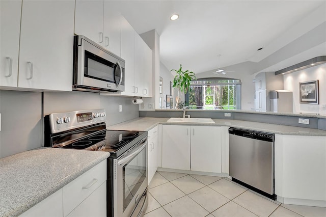 kitchen featuring stainless steel appliances, light stone counters, light tile patterned floors, white cabinets, and vaulted ceiling