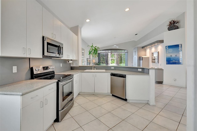 kitchen with stainless steel appliances, white cabinetry, sink, kitchen peninsula, and lofted ceiling