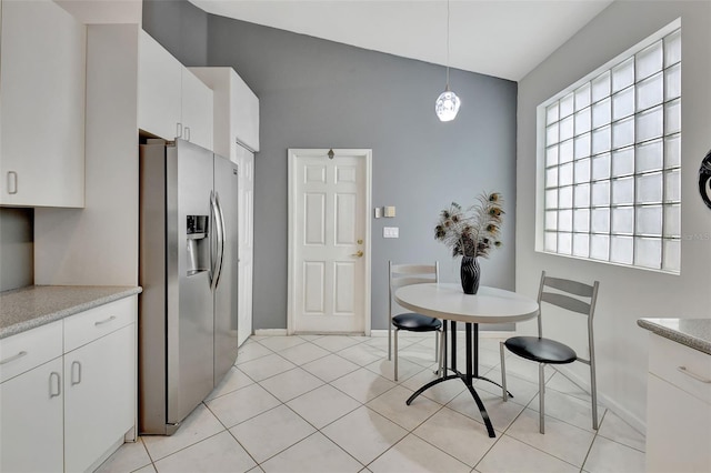 kitchen featuring pendant lighting, stainless steel refrigerator with ice dispenser, lofted ceiling, and white cabinets