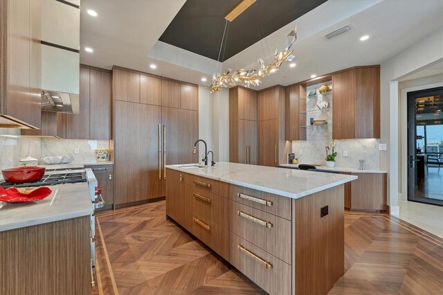 kitchen featuring sink, pendant lighting, a chandelier, a spacious island, and light parquet flooring