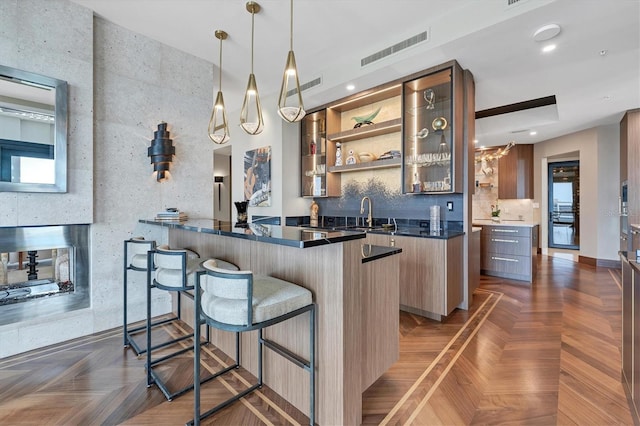 bar with dark parquet floors, sink, and hanging light fixtures