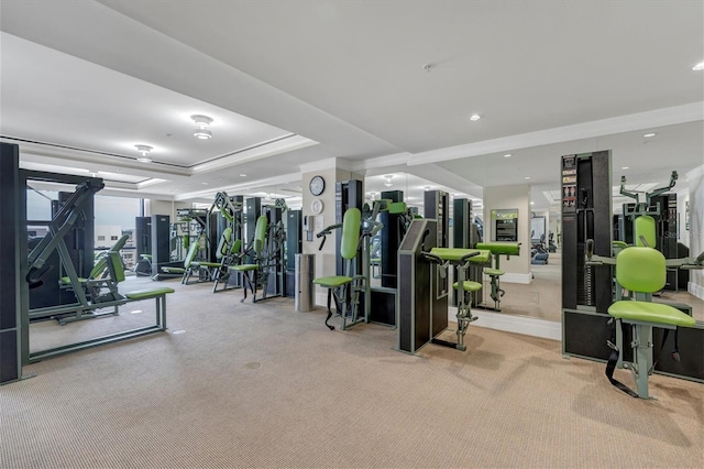 gym featuring a tray ceiling and light colored carpet