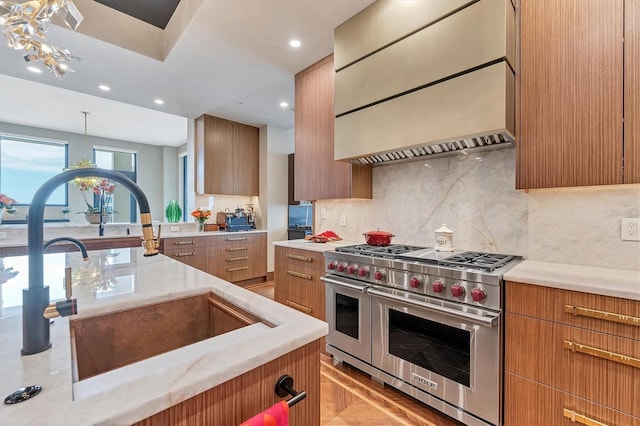 kitchen featuring sink, hanging light fixtures, tasteful backsplash, premium range hood, and range with two ovens