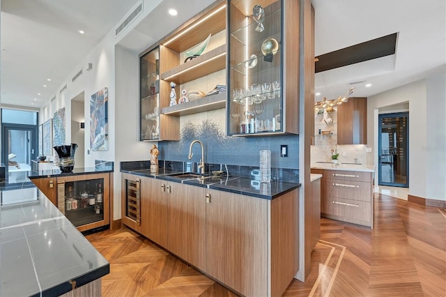 kitchen featuring decorative backsplash, sink, light parquet floors, and beverage cooler