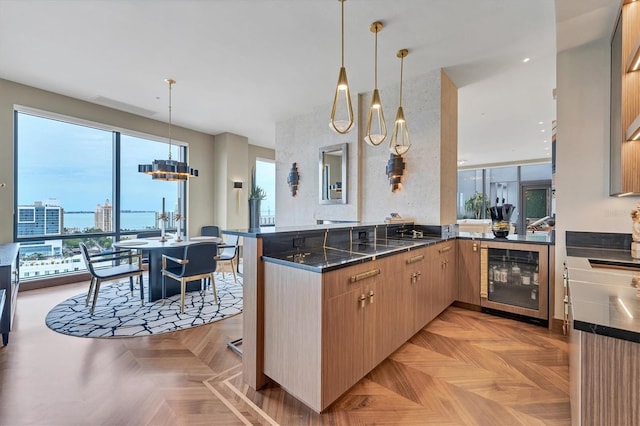 kitchen featuring pendant lighting, light parquet floors, light brown cabinetry, kitchen peninsula, and beverage cooler