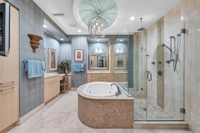 bathroom with a raised ceiling, an inviting chandelier, vanity, and shower with separate bathtub