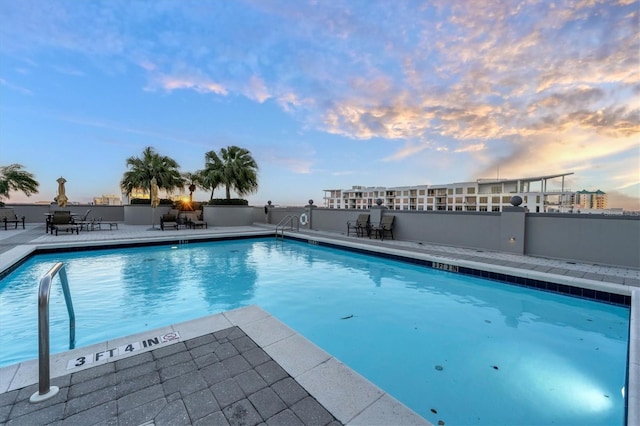 pool at dusk featuring a patio