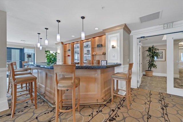 kitchen featuring pendant lighting, dark stone counters, a kitchen breakfast bar, ornamental molding, and kitchen peninsula