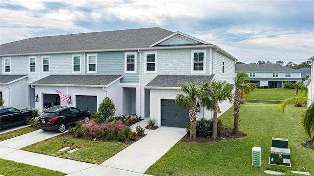 view of front of house featuring concrete driveway, a front lawn, roof with shingles, and a garage