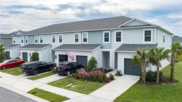 view of property with a garage, a front lawn, driveway, and roof with shingles