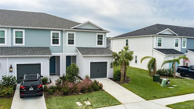 view of front facade featuring driveway, roof with shingles, a front yard, an attached garage, and stucco siding