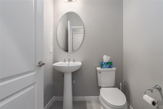 bathroom featuring toilet, baseboards, and a sink