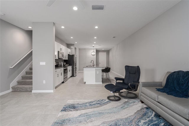 living room featuring light tile patterned flooring, stairs, recessed lighting, baseboards, and visible vents