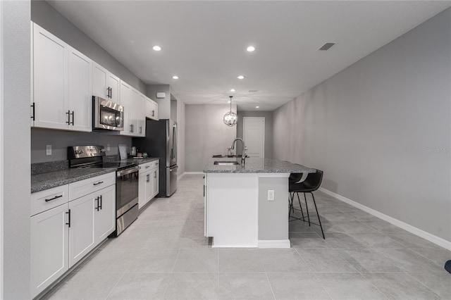 kitchen with sink, white cabinetry, stainless steel appliances, a breakfast bar, and a center island with sink