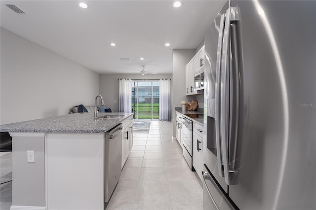 kitchen with white cabinetry, stainless steel appliances, sink, and an island with sink