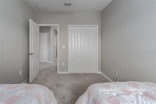 bedroom featuring a closet, a textured ceiling, and light colored carpet