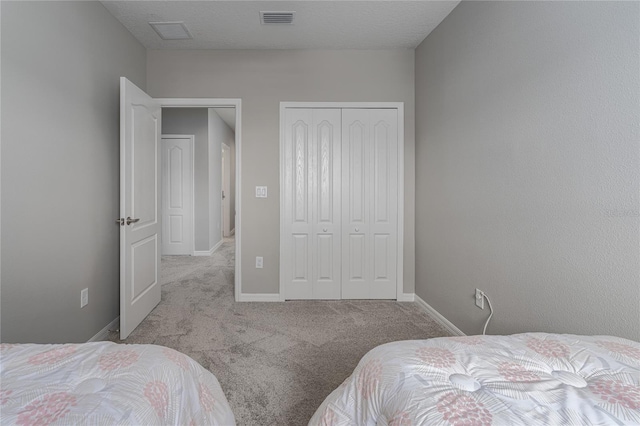 carpeted bedroom featuring visible vents, baseboards, and a closet