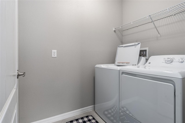 clothes washing area with laundry area, washer and clothes dryer, and baseboards