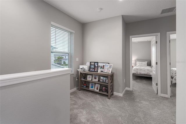 hall featuring visible vents, carpet flooring, and baseboards