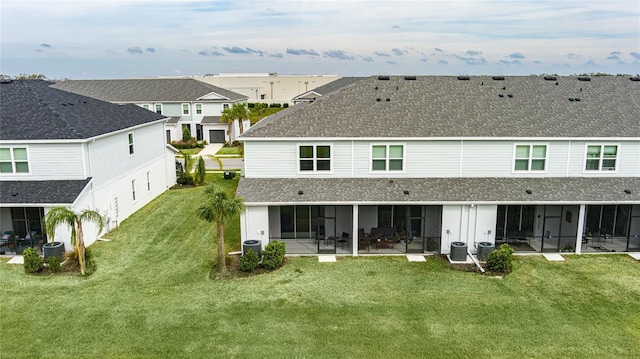 rear view of house with roof with shingles, a yard, a sunroom, and central AC