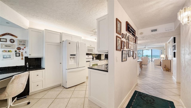 kitchen with a textured ceiling, white cabinetry, light tile patterned floors, and white appliances