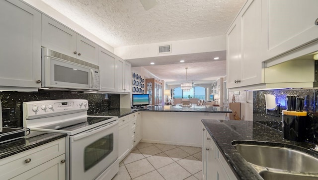 kitchen featuring backsplash, kitchen peninsula, a textured ceiling, white appliances, and white cabinets