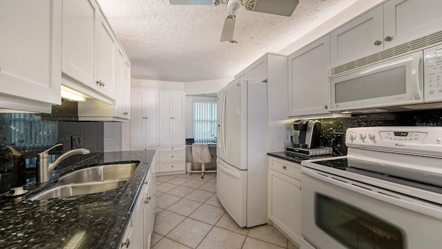 kitchen with dark stone countertops, white cabinetry, sink, and white appliances