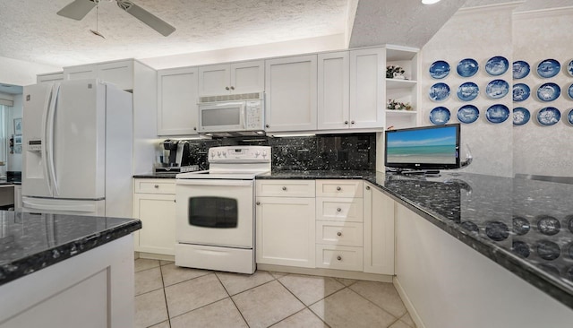 kitchen featuring white appliances, dark stone countertops, light tile patterned floors, a textured ceiling, and tasteful backsplash