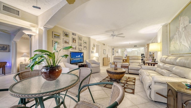 tiled living room featuring decorative columns, ceiling fan, and ornamental molding