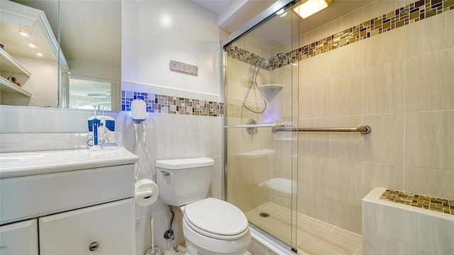 bathroom with vanity, toilet, tile walls, and walk in shower