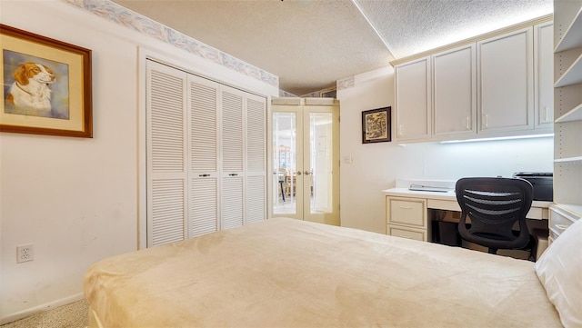 carpeted bedroom with built in desk, french doors, a textured ceiling, and a closet