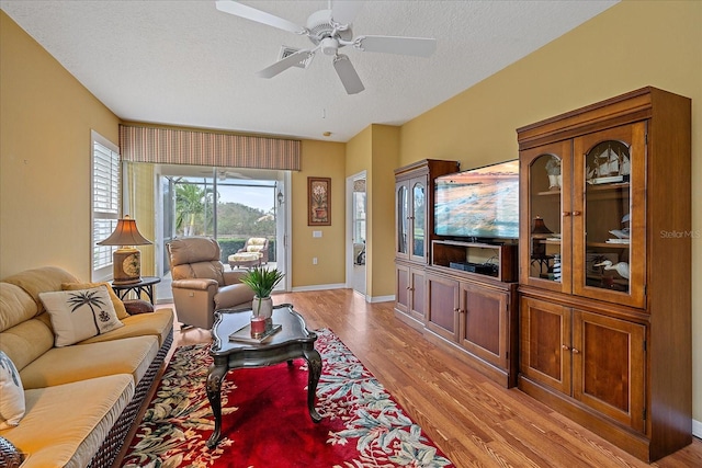 living room featuring a textured ceiling, light hardwood / wood-style floors, and ceiling fan