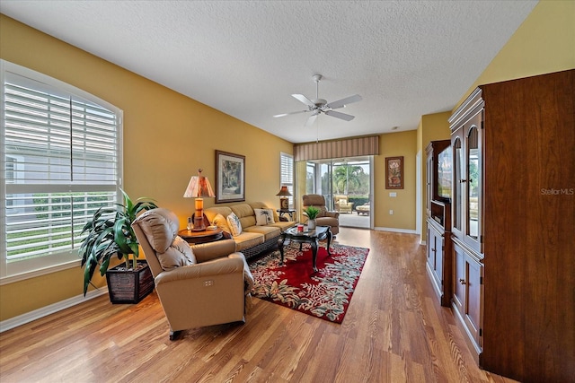 living room featuring a textured ceiling, light wood-type flooring, and ceiling fan