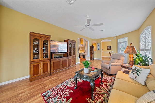 living room with light hardwood / wood-style floors, a textured ceiling, and ceiling fan