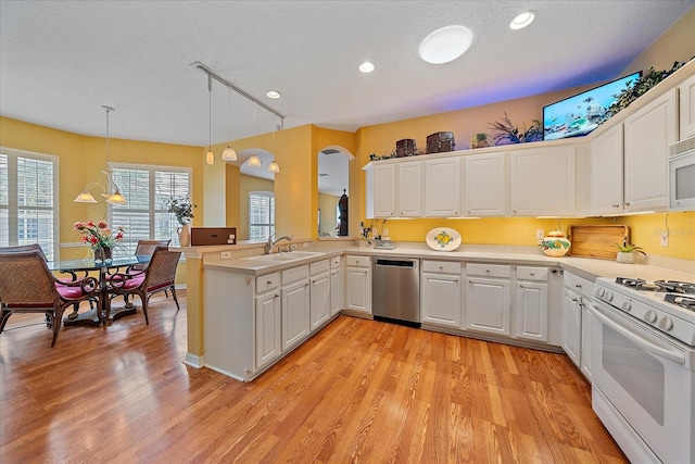 kitchen featuring light hardwood / wood-style flooring, kitchen peninsula, pendant lighting, and white appliances