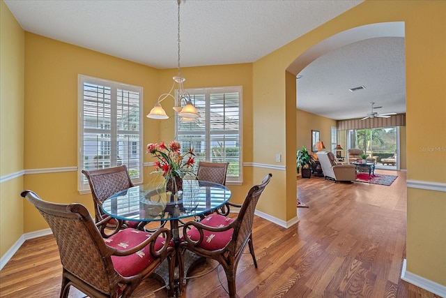 dining room featuring a textured ceiling, hardwood / wood-style flooring, and ceiling fan with notable chandelier