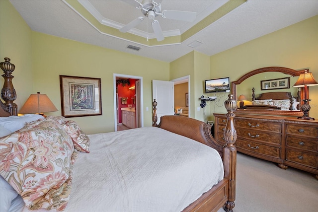 carpeted bedroom with a raised ceiling, ensuite bathroom, and ceiling fan