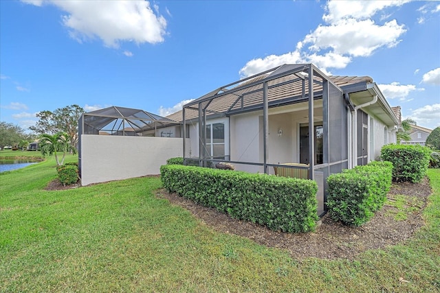 view of home's exterior with a yard and glass enclosure