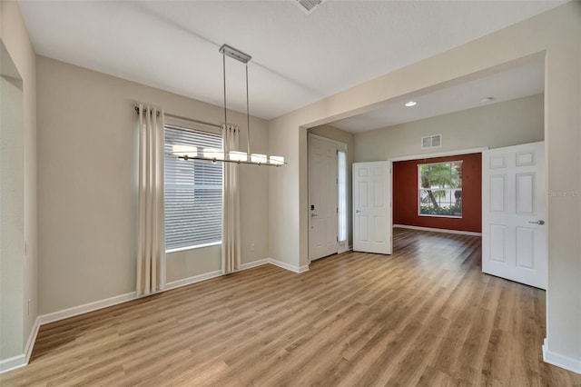 unfurnished dining area with light hardwood / wood-style flooring and a notable chandelier