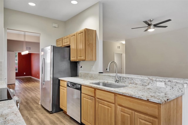 kitchen featuring stainless steel appliances, light stone counters, sink, pendant lighting, and light hardwood / wood-style flooring