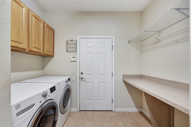 clothes washing area featuring washer and clothes dryer, cabinets, and light tile patterned floors