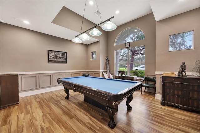 recreation room with a towering ceiling, pool table, and light hardwood / wood-style flooring