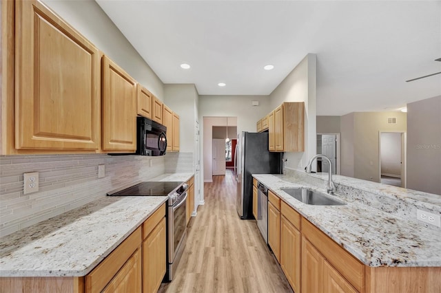 kitchen with light stone counters, sink, backsplash, and stainless steel appliances