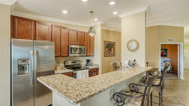 kitchen featuring a kitchen bar, crown molding, appliances with stainless steel finishes, decorative light fixtures, and light stone counters