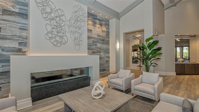 living room with light hardwood / wood-style floors, ornamental molding, tile walls, and a high ceiling