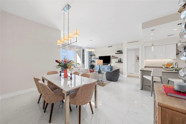 dining area with light marble finish flooring, a chandelier, and baseboards