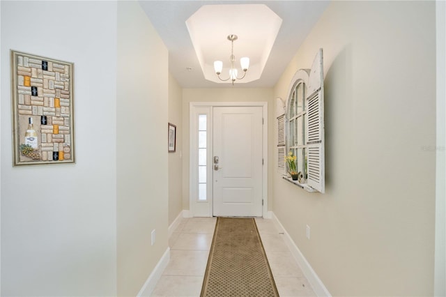 tiled entryway with a raised ceiling and a chandelier