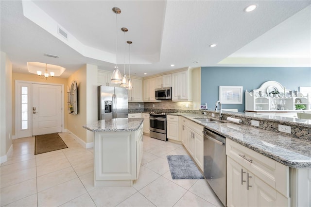 kitchen with pendant lighting, sink, a tray ceiling, and appliances with stainless steel finishes