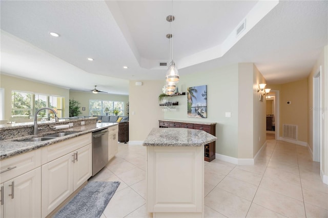 kitchen with pendant lighting, sink, dishwasher, light stone countertops, and a kitchen island